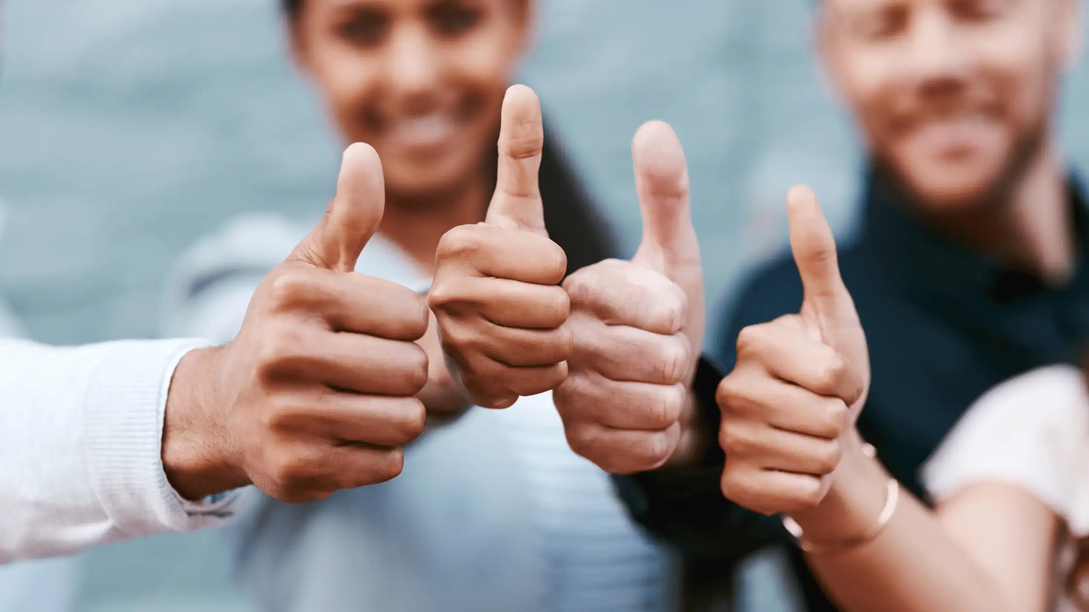 Thumbs up gesture showing approval and positivity; diverse group of people smiling and giving thumbs up at outdoor event.